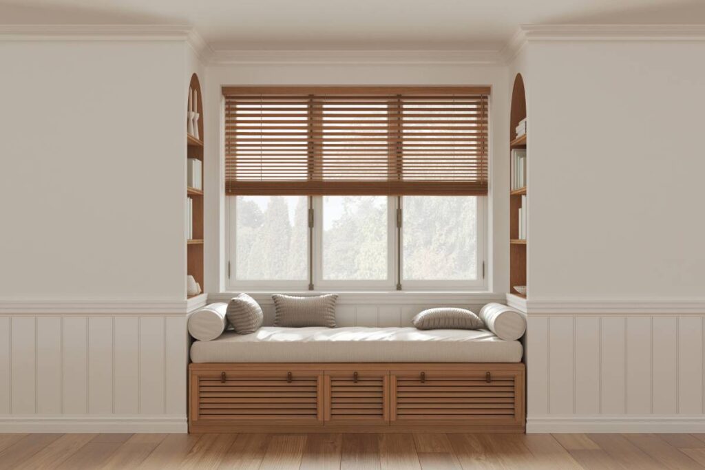 A cozy nook with arched bookshelves, comfortable bench seating, and wood blinds on the window