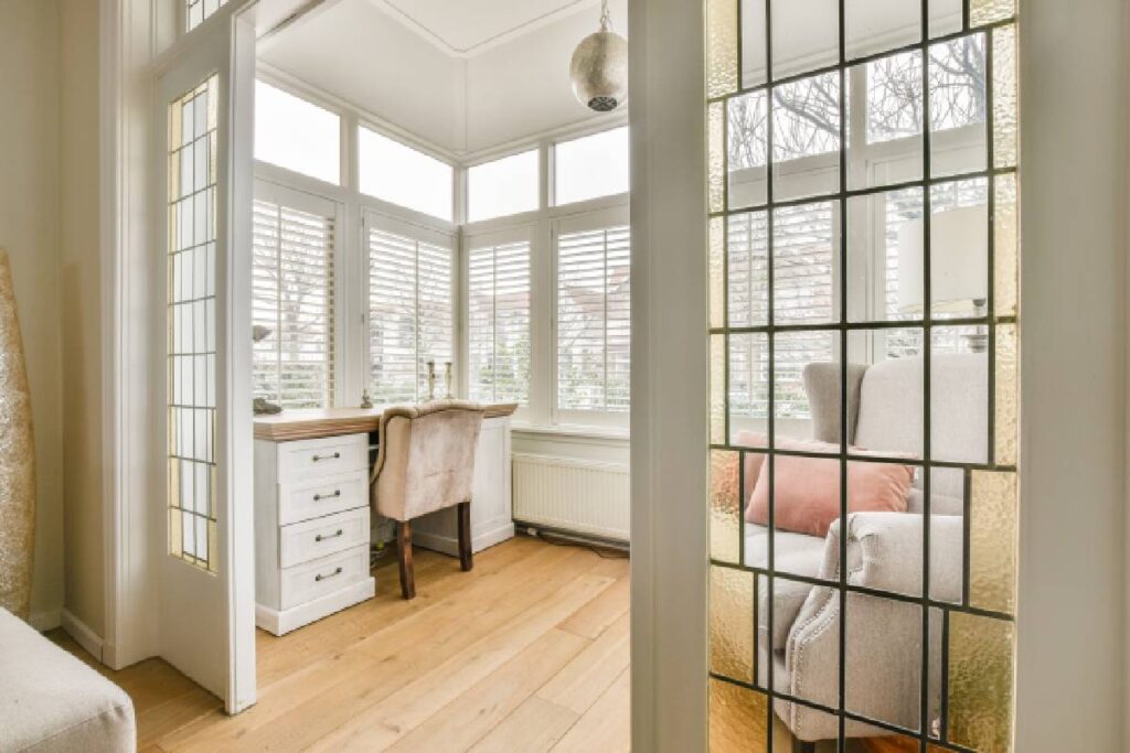 White custom interior shutters on several windows inside a home's bright and airy office