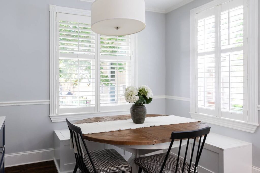 Two sets of white custom shutters for windows in a home's minimalist kitchen