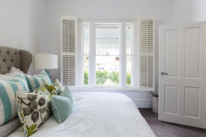 Opened custom interior shutters in a neutral bedroom with pops of blue accents