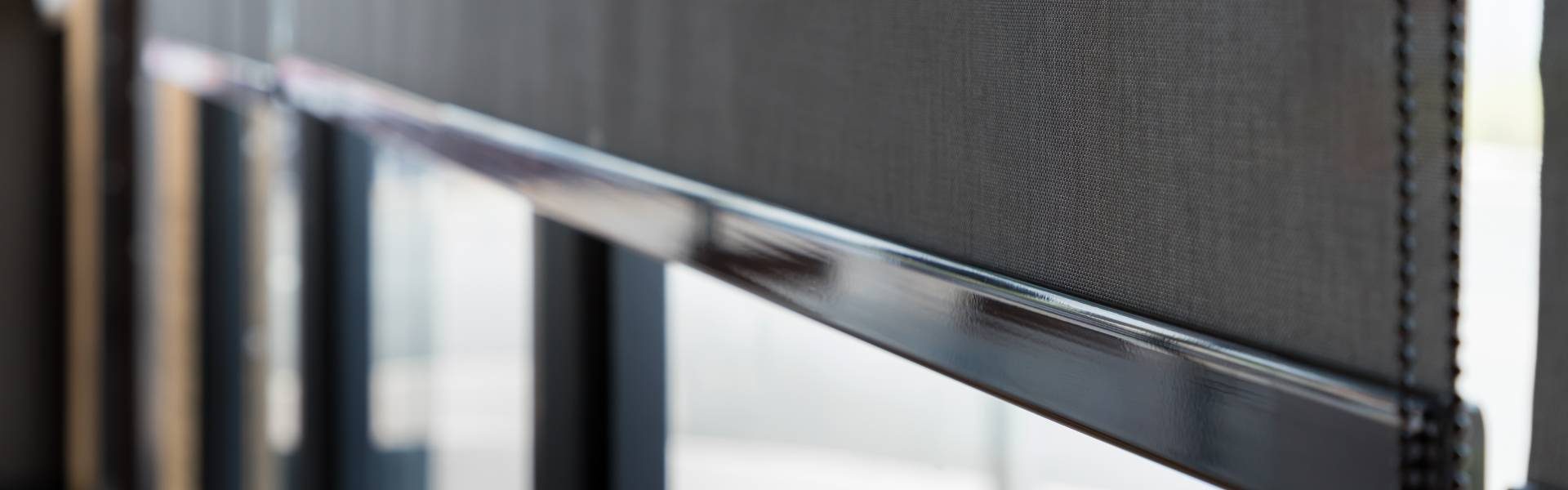 An up-close image of a dark-colored roller shade on a residential window with a beaded loop